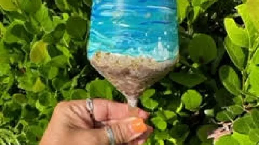 a wine glass painted like the beach with waves and sand
