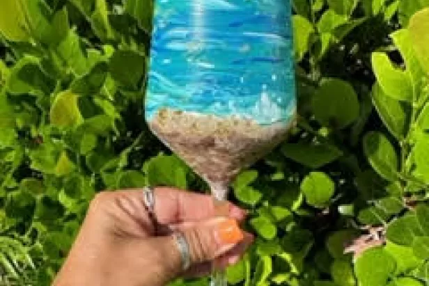 a wine glass painted like the beach with waves and sand
